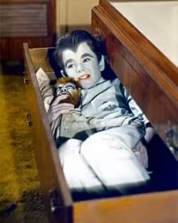 A young boy in a wooden box holding a bottle.