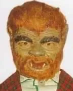 A man with red hair and green eyes wearing a fake werewolf mask.