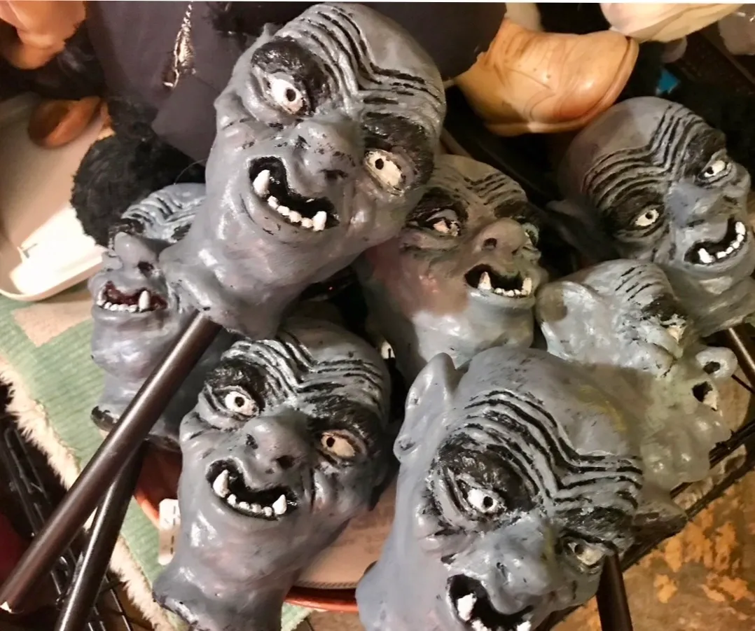 A pile of ceramic faces with evil eyes and mouths.