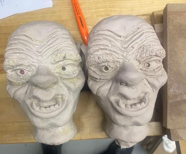 Two clay heads are sitting on a table.