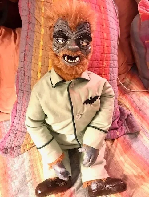 A werewolf doll sitting on top of a bed.